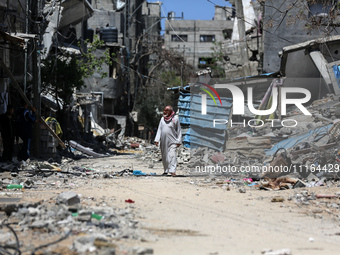 A Palestinian man is walking past a destroyed building in Nuseirat, Gaza Strip, on April 21, 2024, amid ongoing battles between Israel and t...