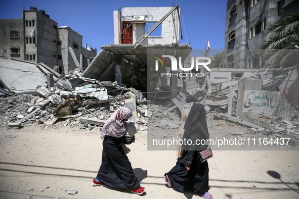 Palestinians are walking past a destroyed building in Nuseirat, Gaza Strip, on April 21, 2024, amid ongoing battles between Israel and the m...