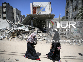 Palestinians are walking past a destroyed building in Nuseirat, Gaza Strip, on April 21, 2024, amid ongoing battles between Israel and the m...