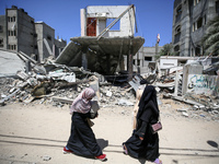 Palestinians are walking past a destroyed building in Nuseirat, Gaza Strip, on April 21, 2024, amid ongoing battles between Israel and the m...