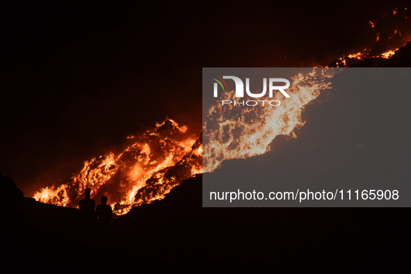 People are looking towards the smoke after a fire broke out at the Ghazipur landfill site, on the outskirts of New Delhi, India, on April 21...