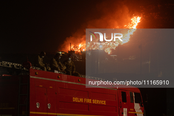 A Fire Brigade van is seen at the Ghazipur landfill site while smoke billows from a fire that has broken out on the outskirts of New Delhi,...