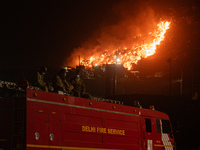 A Fire Brigade van is seen at the Ghazipur landfill site while smoke billows from a fire that has broken out on the outskirts of New Delhi,...