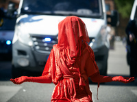 A Red Rebel from Extinction Rebellion is standing in front of riot police in Toulouse, France, on April 21, 2024. Several thousand people ar...