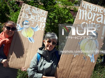 Two women are holding cardboards depicting blue tits with the messages 'Where is justice?' and 'Urgent moratorium'. Several thousand people...