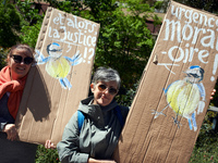 Two women are holding cardboards depicting blue tits with the messages 'Where is justice?' and 'Urgent moratorium'. Several thousand people...