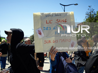 A woman is holding a cardboard sign that reads 'You have the blood of future generations on your hands'. Several thousand people are demonst...