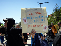 A woman is holding a cardboard sign that reads 'You have the blood of future generations on your hands'. Several thousand people are demonst...