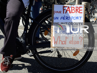 Cyclists are displaying a placard that reads 'For Fabre, an airport, a highway, devastated lands, what else?' as thousands of people are dem...