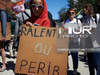 A protester is displaying a cardboard sign with the message ''to slow down or to die'' as several thousand people are demonstrating in the s...