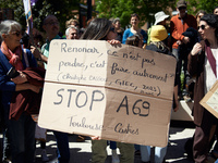 Protesters are holding placards, one of which reads 'to renounce isn't to lose, it's doing differently. Christophe Cassou. IPCC. Stop A69',...