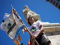 A man is standing near the statue of Pierre-Paul Riquet in Toulouse, holding a flag that reads 'La Voie Est Libre'. Several thousand people...