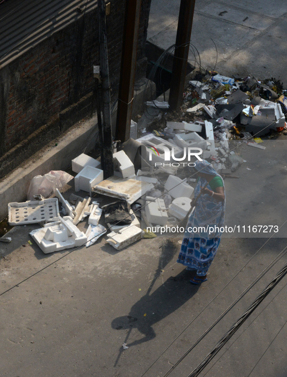 A daily wage worker is cleaning the road where household garbage and waste have been thrown at the roadside area in Siliguri, India, on Apri...