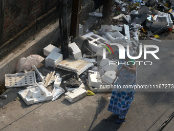 A daily wage worker is cleaning the road where household garbage and waste have been thrown at the roadside area in Siliguri, India, on Apri...