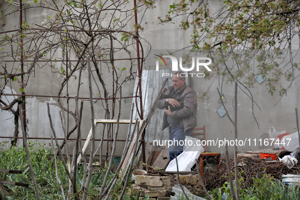 A man is carrying a black cat across a yard in a residential area affected by falling Russian missile debris in the Odesa region, southern U...