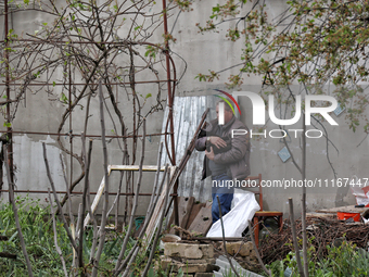 A man is carrying a black cat across a yard in a residential area affected by falling Russian missile debris in the Odesa region, southern U...