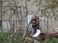 A man is carrying a black cat across a yard in a residential area affected by falling Russian missile debris in the Odesa region, southern U...