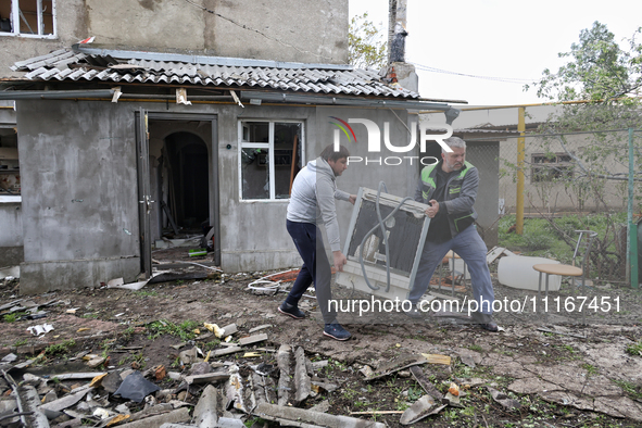 Men are carrying a home appliance outside a building that has been damaged by a Russian missile attack in the Odesa region, southern Ukraine...