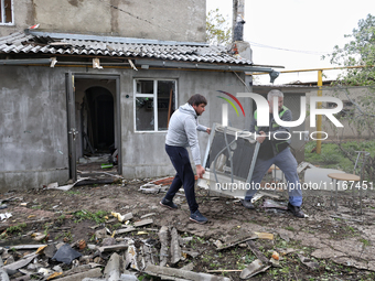 Men are carrying a home appliance outside a building that has been damaged by a Russian missile attack in the Odesa region, southern Ukraine...