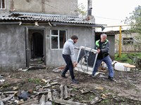 Men are carrying a home appliance outside a building that has been damaged by a Russian missile attack in the Odesa region, southern Ukraine...