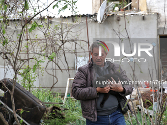 A man is carrying a black cat across a yard in a residential area affected by falling Russian missile debris in the Odesa region, southern U...