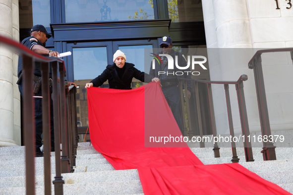 Police watch as a climate activist with the Extinction Rebellion DC organization rolls out a red carpet for Mayor Muriel Bowser during a pro...