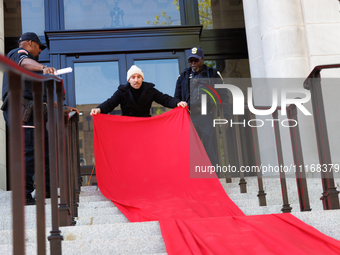 Police watch as a climate activist with the Extinction Rebellion DC organization rolls out a red carpet for Mayor Muriel Bowser during a pro...