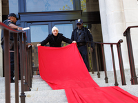 Police watch as a climate activist with the Extinction Rebellion DC organization rolls out a red carpet for Mayor Muriel Bowser during a pro...