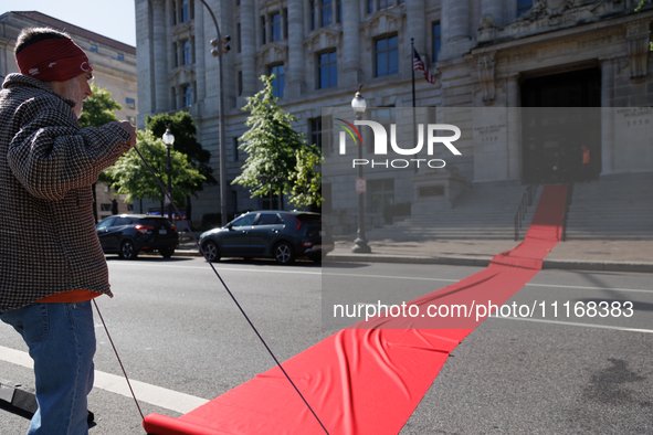 Climate activists with the Extinction Rebellion DC organization roll out a red carpet for Mayor Muriel Bowser during a protest outside of th...