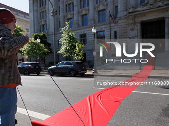 Climate activists with the Extinction Rebellion DC organization roll out a red carpet for Mayor Muriel Bowser during a protest outside of th...