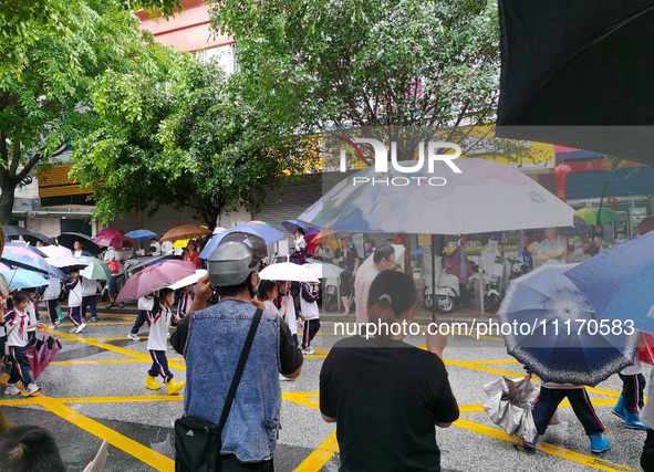 Parents are holding umbrellas to pick up students at the school gate as kindergarten classes resume at noon in Qingyuan, China, on April 23,...