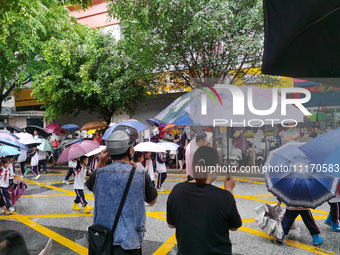 Parents are holding umbrellas to pick up students at the school gate as kindergarten classes resume at noon in Qingyuan, China, on April 23,...