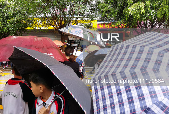 Parents are holding umbrellas to pick up students at the school gate as kindergarten classes resume at noon in Qingyuan, China, on April 23,...