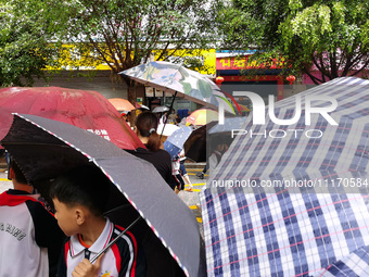 Parents are holding umbrellas to pick up students at the school gate as kindergarten classes resume at noon in Qingyuan, China, on April 23,...