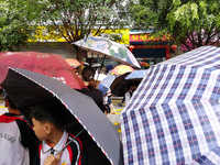 Parents are holding umbrellas to pick up students at the school gate as kindergarten classes resume at noon in Qingyuan, China, on April 23,...