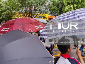 Parents are holding umbrellas to pick up students at the school gate as kindergarten classes resume at noon in Qingyuan, China, on April 23,...