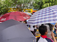 Parents are holding umbrellas to pick up students at the school gate as kindergarten classes resume at noon in Qingyuan, China, on April 23,...