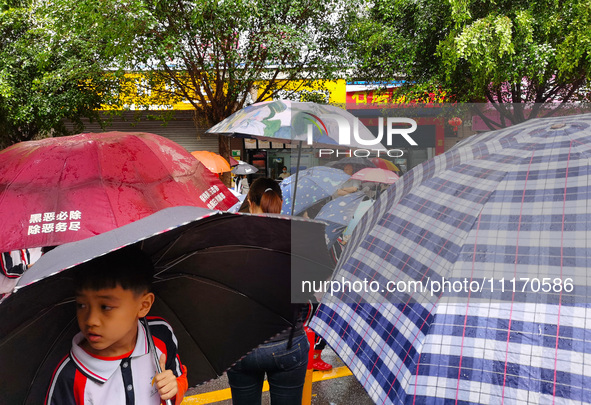 Parents are holding umbrellas to pick up students at the school gate as kindergarten classes resume at noon in Qingyuan, China, on April 23,...