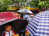 Parents are holding umbrellas to pick up students at the school gate as kindergarten classes resume at noon in Qingyuan, China, on April 23,...