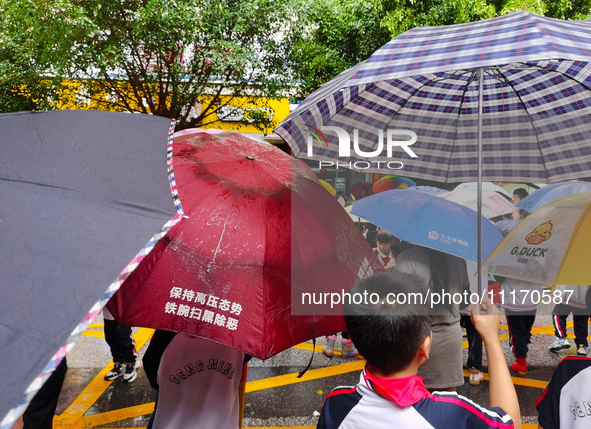 Parents are holding umbrellas to pick up students at the school gate as kindergarten classes resume at noon in Qingyuan, China, on April 23,...