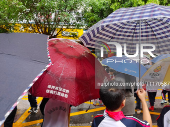 Parents are holding umbrellas to pick up students at the school gate as kindergarten classes resume at noon in Qingyuan, China, on April 23,...