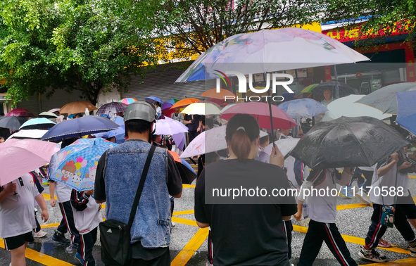 Parents are holding umbrellas to pick up students at the school gate as kindergarten classes resume at noon in Qingyuan, China, on April 23,...