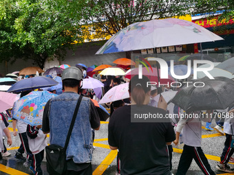 Parents are holding umbrellas to pick up students at the school gate as kindergarten classes resume at noon in Qingyuan, China, on April 23,...