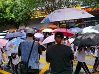 Parents are holding umbrellas to pick up students at the school gate as kindergarten classes resume at noon in Qingyuan, China, on April 23,...