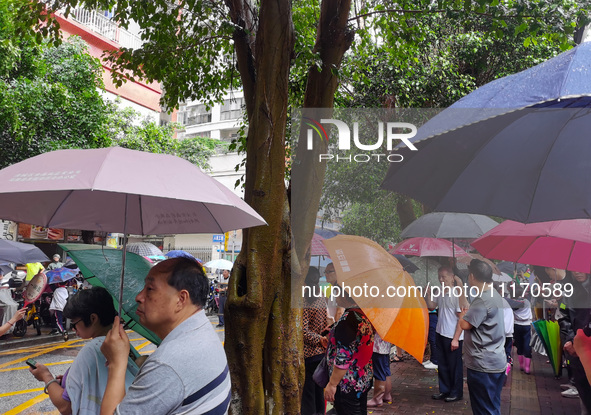 Parents are holding umbrellas to pick up students at the school gate as kindergarten classes resume at noon in Qingyuan, China, on April 23,...