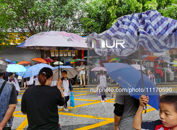 Parents are holding umbrellas to pick up students at the school gate as kindergarten classes resume at noon in Qingyuan, China, on April 23,...