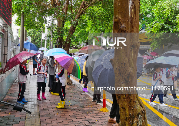 Parents are holding umbrellas to pick up students at the school gate as kindergarten classes resume at noon in Qingyuan, China, on April 23,...