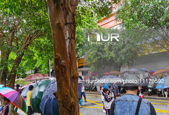 Parents are holding umbrellas to pick up students at the school gate as kindergarten classes resume at noon in Qingyuan, China, on April 23,...