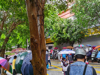 Parents are holding umbrellas to pick up students at the school gate as kindergarten classes resume at noon in Qingyuan, China, on April 23,...