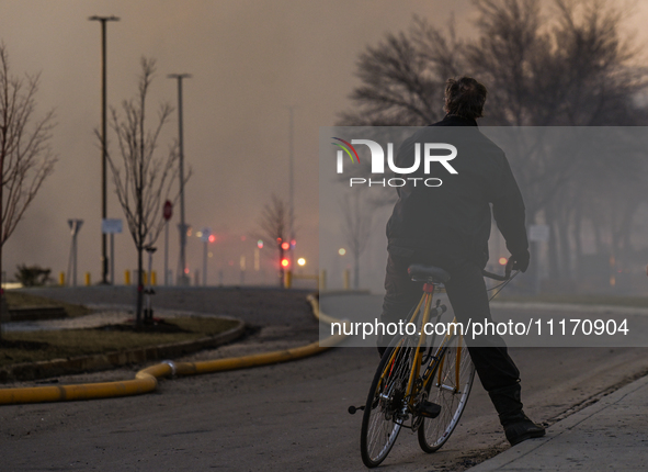 EDMONTON, CANADA - APRIL 22:
A man on his bike observes firefighters combating flames that tore through Edmonton's historic Hangar 11 on Mon...